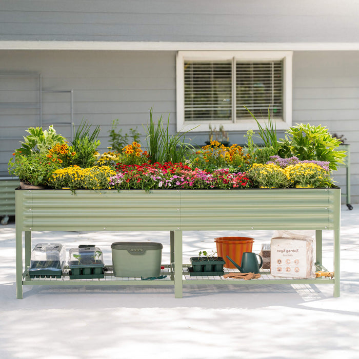 Vego Garden elevated green metal raised garden bed filled with vibrant flowers. Shelf below holds seed starting kits, coco mulch, and tools.