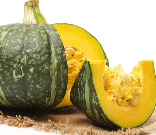 Whole and sliced green Kabocha squash with bright yellow flesh and seeds. Fresh healthy winter vegetable.