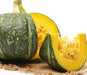 Whole and sliced green Kabocha squash with bright yellow flesh and seeds. Fresh healthy winter vegetable.