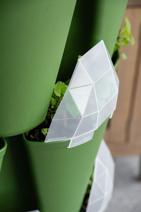 Green vertical garden planter with young plants and a translucent, geometric GreenStalk plant marker.