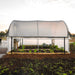 Shade net hoop house protecting raised garden beds with growing organic vegetables: lettuce, kale, and greens.