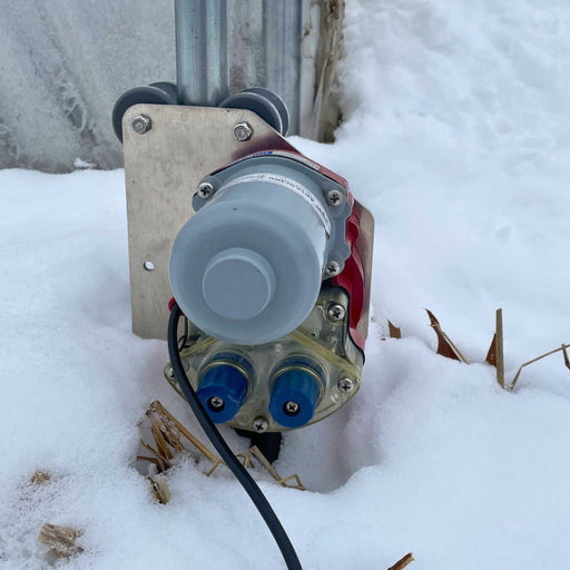 Greenhouse roll-up side wall motor in snow. Automated ventilation system for winter farm operations.