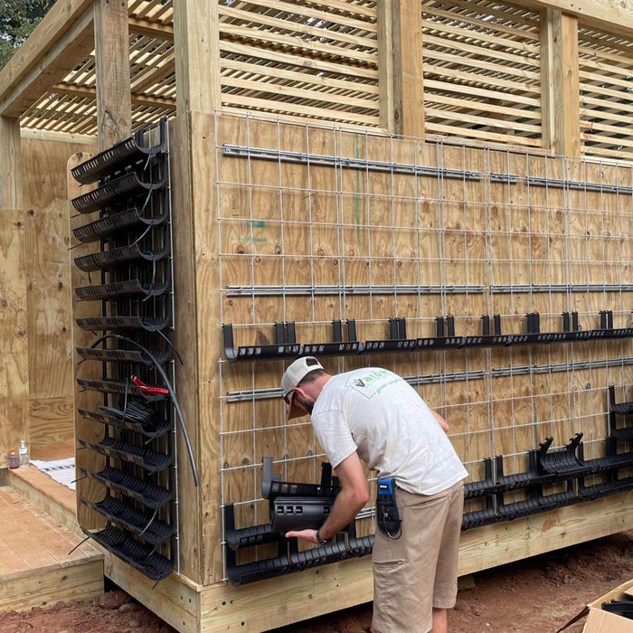 Man installing modular vertical garden planters on a wood wall with a grid system and overhead pergola.