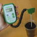 Rapitest digital soil pH, fertility, temperature analyzer (showing 6.8 pH) held, with probe inserted into dark soil.
