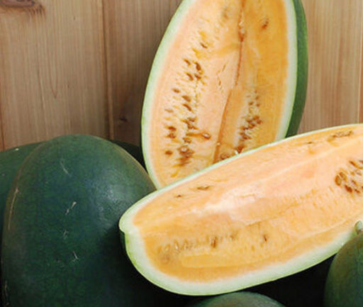 Golden watermelon halves with seeds, dark green rinds, fresh sweet fruit on wood.