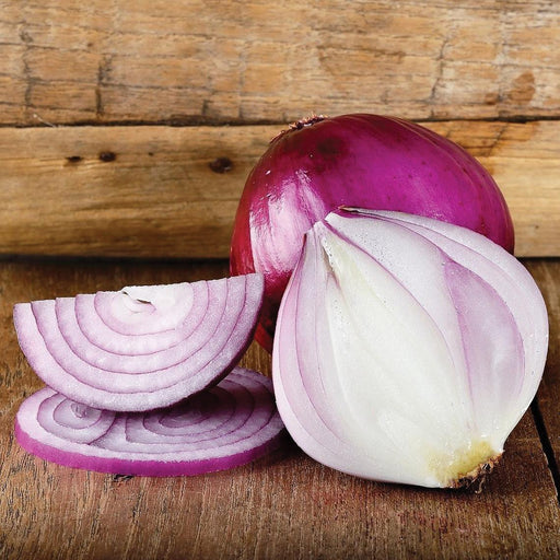 Vibrant whole red onion, a halved onion revealing layers, and sliced red onion rings on wood.