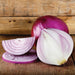 Vibrant whole red onion, a halved onion revealing layers, and sliced red onion rings on wood.