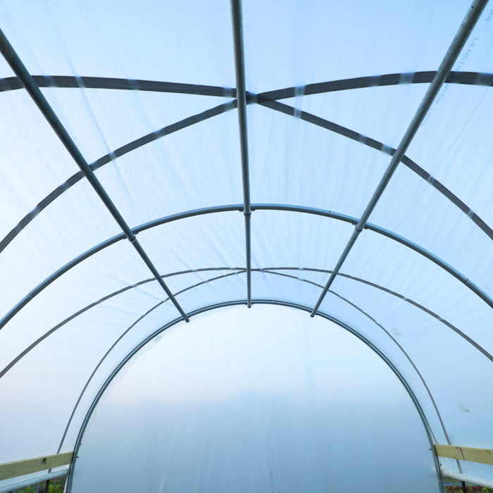 Hoop house interior with translucent plastic covering and metal frame. Ideal for protected cultivation and year-round growing.