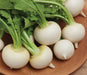 Fresh white turnips with vibrant green leaves on a wooden surface. Healthy root vegetables.