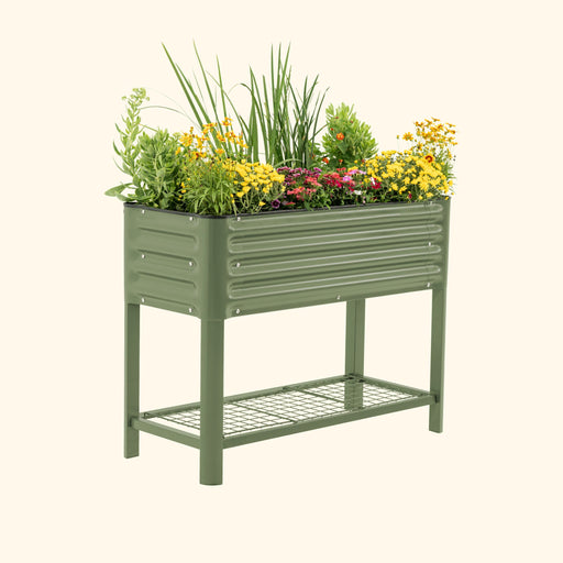 Olive green elevated garden bed planter with diverse colorful flowers and green foliage, featuring a convenient lower shelf.