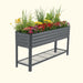 Dark gray corrugated metal raised garden bed with colorful flowers and green plants. Elevated planter with storage shelf.