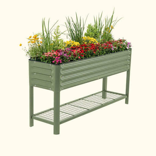 Green corrugated raised garden bed filled with colorful flowers and plants, featuring a lower wire storage shelf.