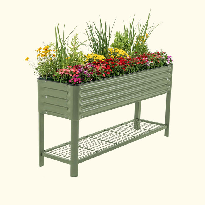 Green corrugated raised garden bed filled with colorful flowers and plants, featuring a lower wire storage shelf.