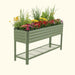 Green corrugated raised garden bed filled with colorful flowers and plants, featuring a lower wire storage shelf.