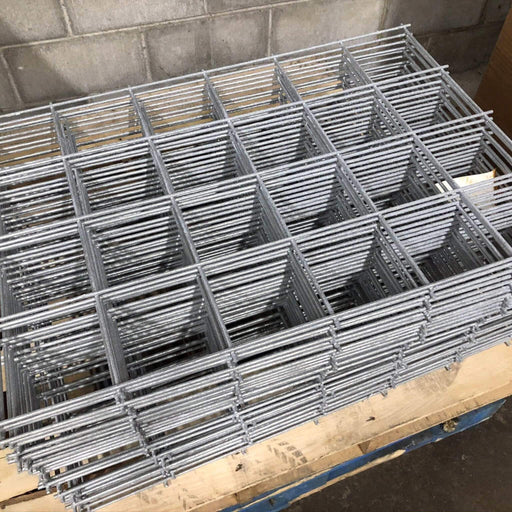 Stacked galvanized welded wire mesh panels on a wooden pallet. Durable steel for construction, fencing, reinforcement.