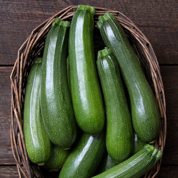 Green zucchini in a brown wicker basket. Fresh organic summer squash, healthy produce for cooking.