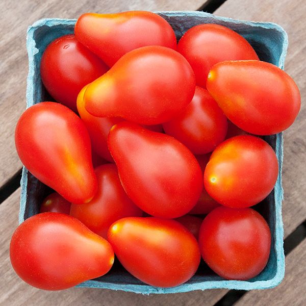 Fresh red pear and grape tomatoes in a blue market basket. Ripe garden produce.