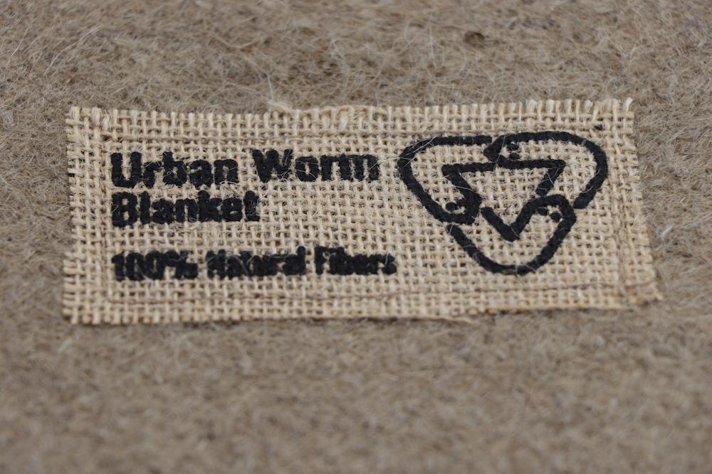 Urban Worm Blanket tag: 100% Natural Fibers and a compost symbol. Perfect for eco-friendly worm farming and gardening.