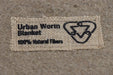 Urban Worm Blanket tag: 100% Natural Fibers and a compost symbol. Perfect for eco-friendly worm farming and gardening.