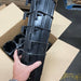 Hand holds stacked black plastic automotive components with clips, packing them in a box. Warehouse shipping.