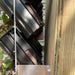 Black vertical garden planters with green plants mounted on a wood fence. Space-saving modular wall garden system.