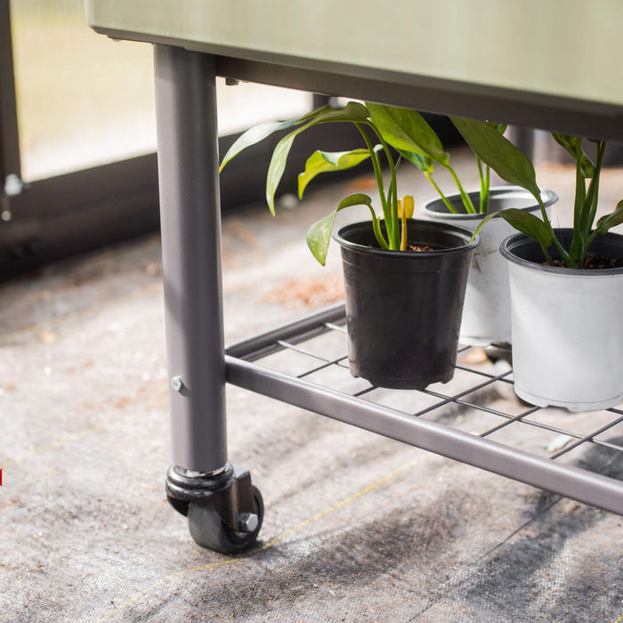 Olive green mobile raised planter with potted plants on a metal grid shelf in a nursery.