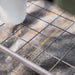 Dark grey metal wire grid shelf with a white pot, perfect for plants, greenhouse, or general storage.