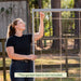 Woman assembling a garden trellis with jute twine for vertical plant support outdoors.