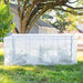 White portable mini greenhouse with zipper on green grass, protecting plants. Outdoor garden plant cover.