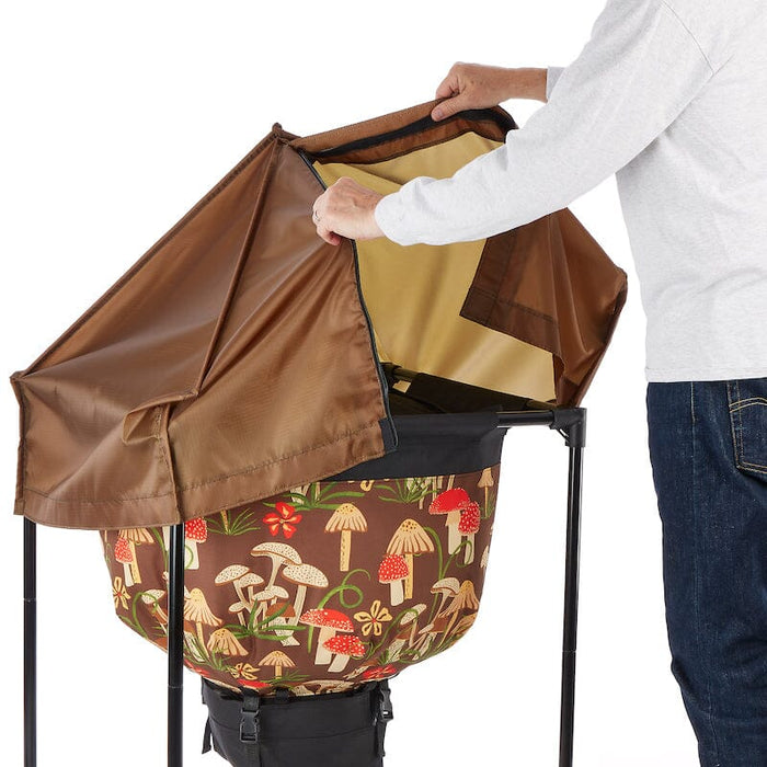 Hands opening a brown lid on a garden cart with a mushroom-patterned bag. Ideal for yard waste, leaves, composting.