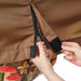 Hands zipping brown outdoor cover, revealing mushroom pattern lining with hook-and-loop fasteners for secure closure.