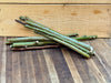 Fresh green & brown woody plant cuttings, some with red buds, on a dark wood surface, against a light wood crate.