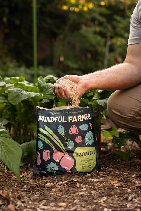 Gardener applying Mindful Farmer AZOMITE mineral amendment to plants. Great for soil health & robust garden growth.