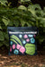 Mindful Farmer AZOMITE Mineral Amendment 10lb bag on garden soil, surrounded by lush green plants.