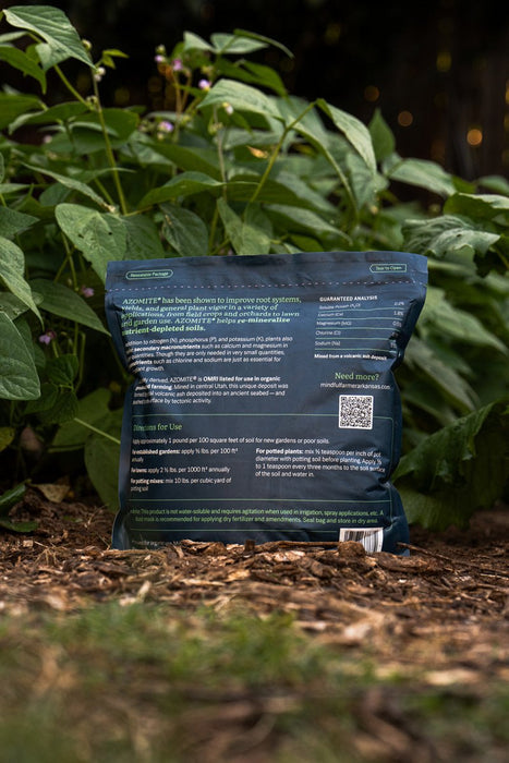 AZOMITE organic mineral fertilizer bag on mulch, improving plant health and soil nutrients for gardens.