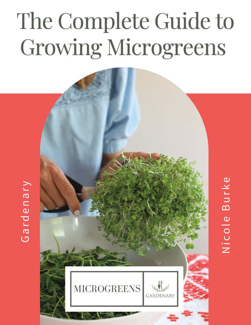 The Complete Guide to Growing Microgreens book by Gardenary. Person harvesting fresh microgreens with scissors.