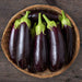 Fresh purple eggplants in a woven basket. Organic aubergine produce on rustic wood.