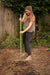 Smiling woman gardener preparing soil with green hoe in backyard garden bed.