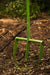 Green metal digging fork in dark garden soil with leaf litter and irrigation. Garden tilling tool.