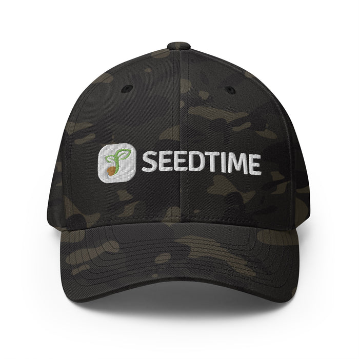Dark camo Seedtime baseball cap with embroidered white logo and green sprout design.