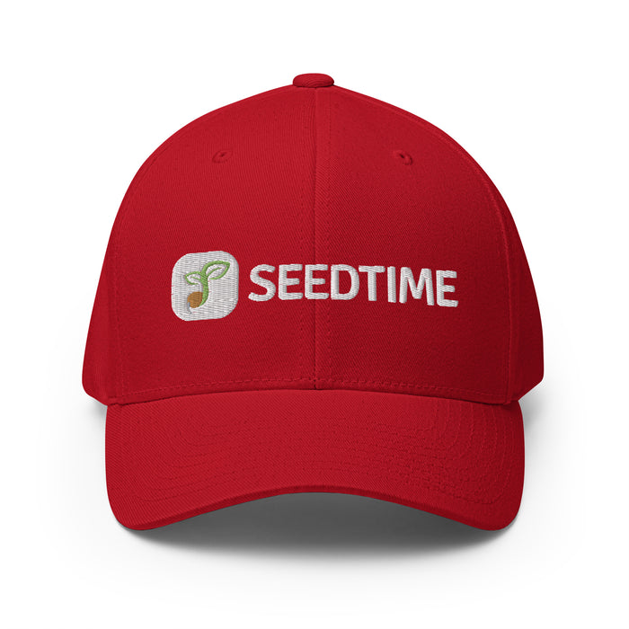 Red Seedtime baseball cap with embroidered white logo featuring a green sprout. Gardening apparel.