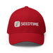 Red Seedtime baseball cap with embroidered white logo featuring a green sprout. Gardening apparel.