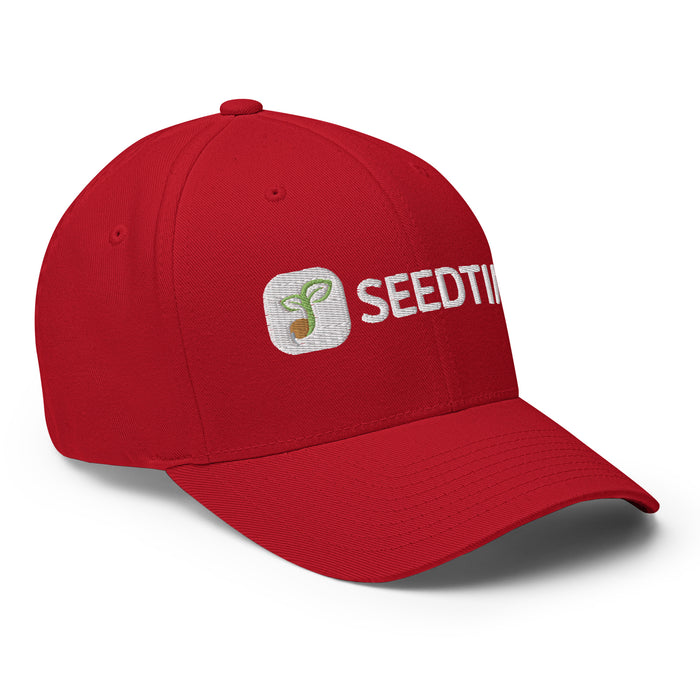 Red baseball cap featuring white embroidered SEEDTIME logo and green sprout icon.