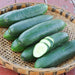Fresh dark green cucumbers, some sliced, in a rustic woven basket. Healthy garden vegetables.