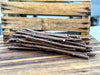 Bundled woody plant cuttings for propagation or grafting on a wooden table, with a rustic crate.