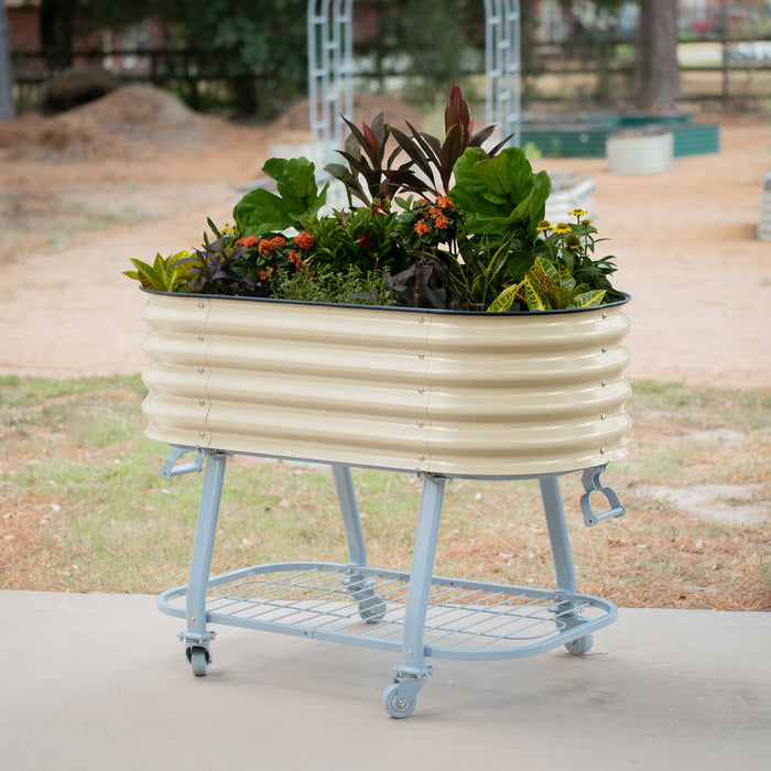 Outdoor cream corrugated metal mobile raised garden bed with various plants, on a wheeled stand and lower shelf.