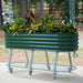 Green corrugated metal raised garden bed on wheels, full of diverse plants and flowers, ideal for patio or deck.