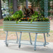 Mobile sage green corrugated metal raised garden bed with storage shelf and vibrant plants.