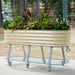 Portable beige corrugated steel raised garden bed with diverse plants and flowers on a grey wheeled stand.