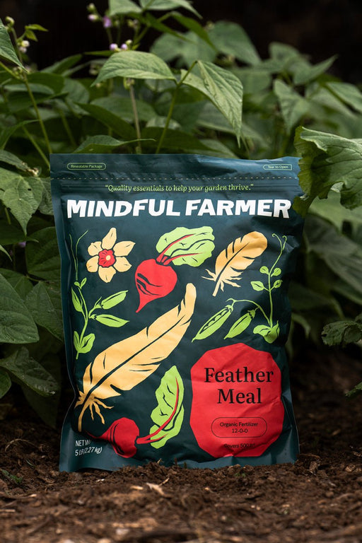 Mindful Farmer Feather Meal 12-0-0 organic fertilizer bag (5lb) with feather & beet art in garden soil.